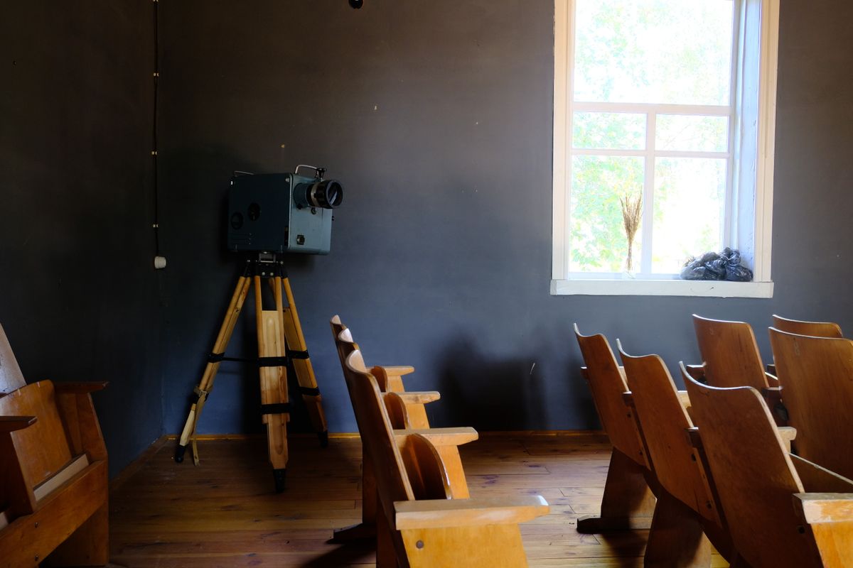 Un projecteur de cinéma face à des chaises en bois