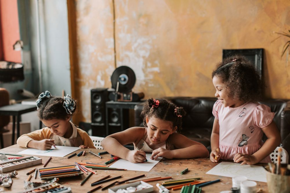 Des enfants dessinent autour d'une table d'atelier