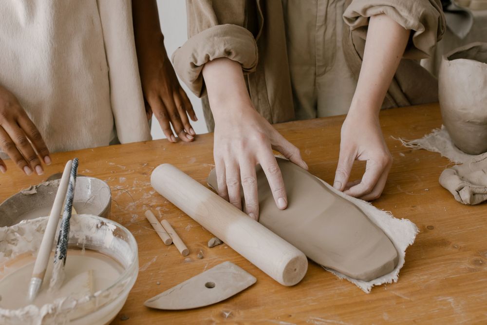 Des mains qui façonnent une pièce sur un plan de travail d'atelier